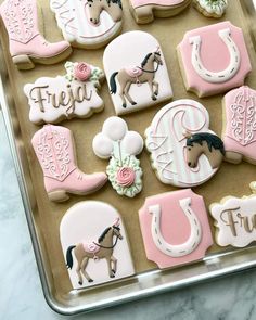 decorated cookies in the shape of horses and horseshoes on a cookie sheet with frosting