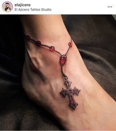 a woman's foot with a rosary and cross tattoo on the side of it