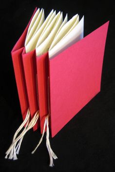 an open red book with tassels on the front and back pages, sitting on a black surface