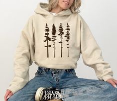 "Pine Tree Forest Sweatshirt, Camp Sweatshirt, Hiking Sweatshirt, Nature Lover Gift, Adventure Hoodie, Hiking Gift, Nature Hoodies Description Due to the nature of the fabric as well as your monitor or mobile screen colors may differ slightly. Our tees and more are handcrafted one at a time. It is therefore very rare to create identical items so you may find minor distinctions that make your SassyPantsTees items special and truly one-of-a-kind. All sales are final. Cancellations, Refunds and Exc Casual Hoodie With Letter Print For Camping, Cozy Hoodie For Outdoor, Cozy Hoodie Top For Outdoor, Long Sleeve Cotton Hoodie For Camping, Casual Cotton Hoodie For Camping, Cozy Outdoor Hoodie Top, Cotton Long Sleeve Hoodie For Camping, White Long Sleeve Sweatshirt For Camping, Forest Sweatshirt