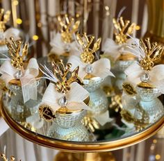 small glass vases with gold and white bows on them are sitting on a table