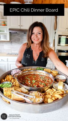 a woman holding a large metal pan filled with food