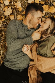 a man and woman laying on the ground with their noses close to each other as they kiss