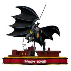 a batman statue on top of a boat with a bat flying over it's head