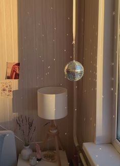 a room with a mirror ball hanging from the ceiling next to a lamp on a table