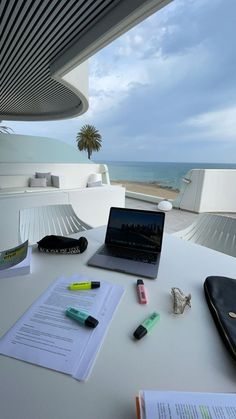 an open laptop computer sitting on top of a white table next to a notebook and pen