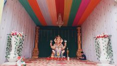 there is a statue of ganesh in the middle of a room with colorful curtains