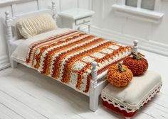 there is a crocheted bed with two pumpkins on the foot board and an afghan