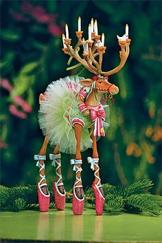 a reindeer figurine wearing pink shoes and a tutu skirt with candles in its mouth