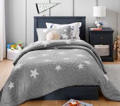 a child's bedroom with grey bedding and white stars on the comforter