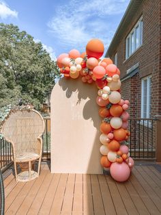 an arch made out of balloons is on the back deck with a chair and table