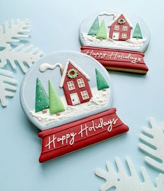 two decorated christmas cookies sitting on top of a blue table next to snowflakes