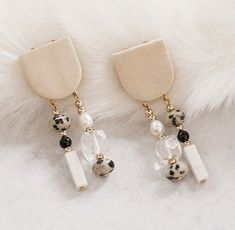 two pairs of white and black beaded earrings sitting on top of a fur rug