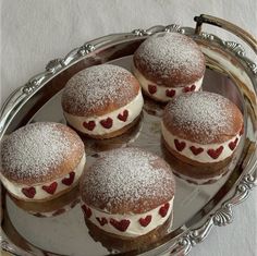 four pastries on a silver platter covered in powdered sugar and red hearts