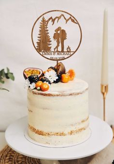 a white cake topped with a wooden sign and fruit