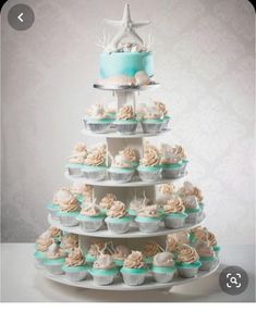 a three tiered cake with cupcakes on the bottom and starfish on top