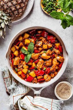 pineapple chicken and peppers in a skillet on a table with other food items