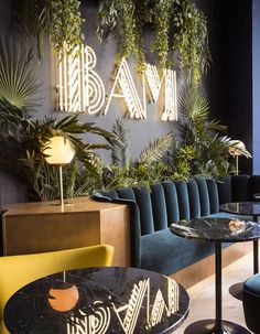 the interior of a restaurant with green plants on the wall and blue velvet seating area