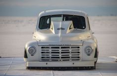 an old white truck is parked in the snow near some water and ice floes