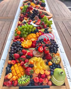 a long wooden tray filled with lots of different types of fruit