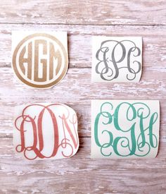 three different monogrammed stickers on a wooden surface