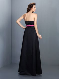 a woman in a strapless black dress is standing with her hands on her hips