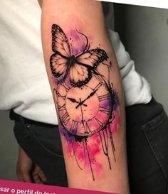 a tattoo with a clock and butterfly on it's arm that is painted in pink and purple watercolors