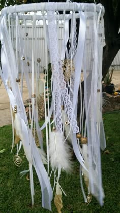 a white wind chime hanging from the side of a tree on top of grass