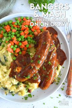 a white plate topped with meat covered in gravy next to carrots and mashed potatoes