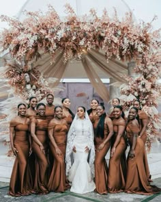 a group of women standing next to each other in front of a white arch covered with flowers