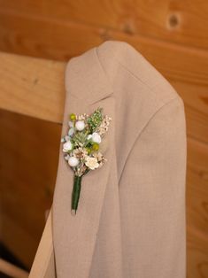 a boutonniere with white flowers and greenery on the lapel of a suit