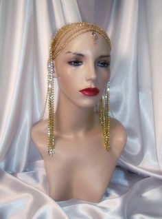 "This luxurious headpiece features layers of brilliant gold rhinestones that drape down the sides and back, encircling the head for a dramatic effect. A brilliant rhinestone pendant accents the center of the headpiece for added luster (pendant may vary in size and shape). The piece is held in place with a rhinestone trimmed headband and its weightiness allows it to sit comfortably atop the head with the assistance of hair/bobby pins. This piece is both elegant and stylish, suitable for formal or Gold Crystal Embellished Headpieces For Wedding, Elegant Gold Headpiece With Rhinestones, Gold Rhinestone Headpieces For Party, Adjustable Glamorous Gold Headpieces, Gold Crown Headpiece With Rhinestones, Glamorous Gold Wedding Headpiece, Cleopatra Headpiece, Cleopatra Wig, Egyptian Collar