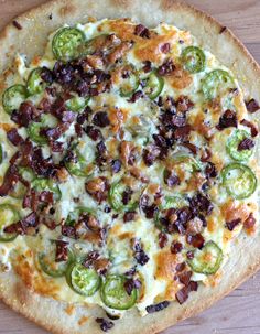 a pizza topped with cheese, bacon and jalapenos on top of a wooden table