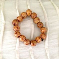 a close up of a beaded bracelet on a white cloth with an orange flower