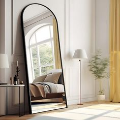 a large mirror sitting on top of a wooden floor next to a table and lamp