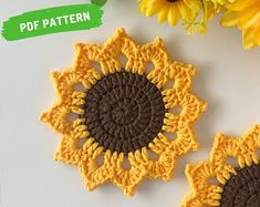 two crocheted sunflowers sitting on top of a table next to yellow flowers