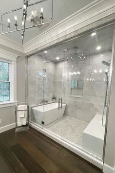 a bathroom with a large glass shower door and wooden flooring in front of the bathtub