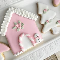 some decorated cookies are on a white platter with pink and white frosted icing