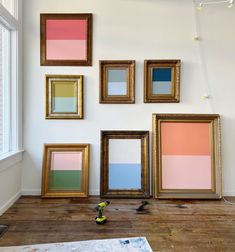 four framed art pieces on the wall in front of a window with paintbrushes