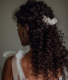 the back of a woman's head with curly hair and flowers in her hair