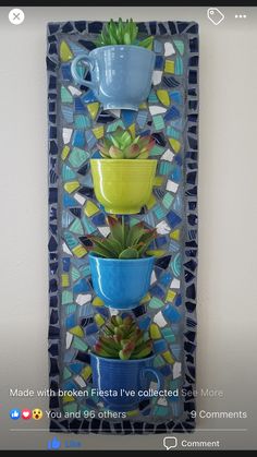 a blue and yellow wall hanging with succulents on it's side