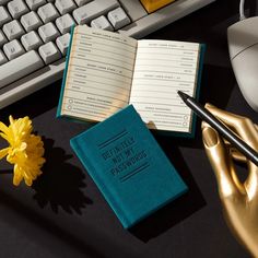 an open book sitting on top of a desk next to a keyboard and mouse with a yellow flower