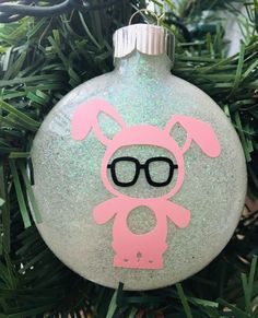 a glass ornament with a pink bunny wearing glasses on it's face