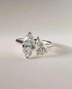 two pear shaped diamond engagement rings on a white surface