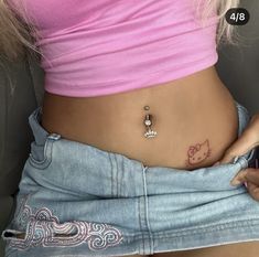 a woman with a hello kitty tattoo on her stomach holding a cell phone in her hand