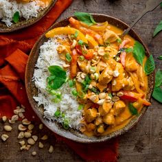 two bowls filled with rice, chicken and vegetables on top of a wooden table next to orange napkins