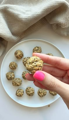 a woman's hand holding a cookie on a plate