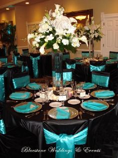 the tables are set with black and turquoise linens, white flowers in a tall vase