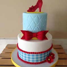 a three tiered cake with red bows and a high heel shoe on the top