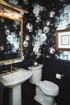 a black and white bathroom with floral wallpaper